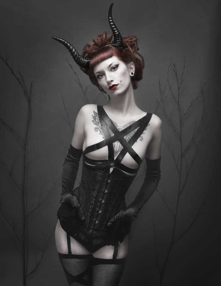 Egan wearing black horns, gloves, and corset with her red hair in dreads for Gothesque Magazine editorial