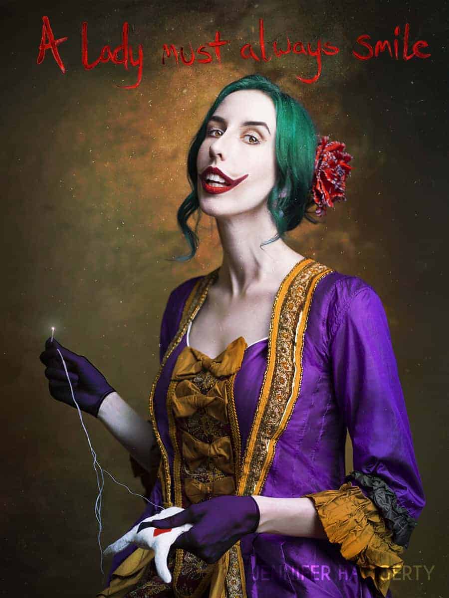 A lady must always smile is painted in blood above Jennifer's green hair, she is wearing a Victorian purple and orange gown and sewing a Harley Quinn ragdoll in this Joker portrait