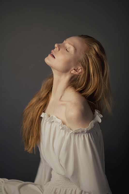Portrait of woman with red hair and wearing a white dress